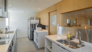 A modern kitchen with white cabinetry, stainless steel appliances, and a built-in dishwasher. - Mangrove Dongdaemun - Hostel (Seoul)