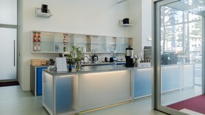 A modern reception desk with a glass partition, a coffee machine, and a shelf with bottles. - Mangrove Dongdaemun - Hostel (Seoul)