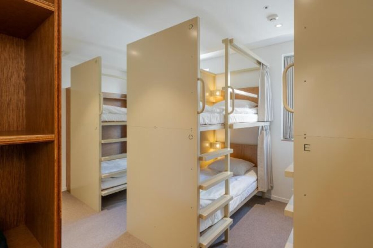 Ein Zimmer mit Etagenbetten, Holzregalen und einem Fenster.
