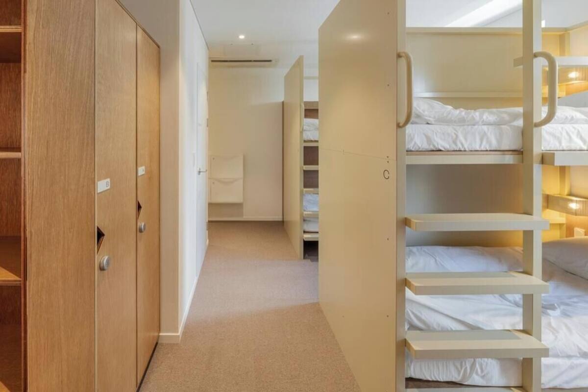 Une chambre d’hôtel avec une armoire en bois, un dressing et un lit superposé doté d’une tête de lit.
