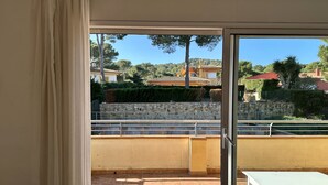 Un balcon donnant sur un mur de pierre, avec un sol carrelé et une table blanche.