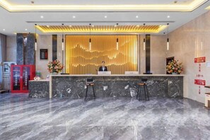A hotel reception area with a marble counter, two bar stools, and a decorative wall with vertical lines. - prosperous horse hotel (Kunming)