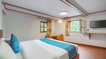 Una habitación de hotel con una cama, una silla, un televisor y dos ventanas.