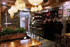 Eine Bar mit Holzkuben, hängenden Lampen und einer Ziegelwand.
