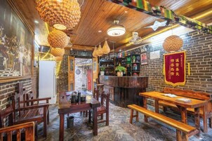 Interior de restaurante con mesas y sillas de madera, lámparas colgantes y una pared de ladrillo.
