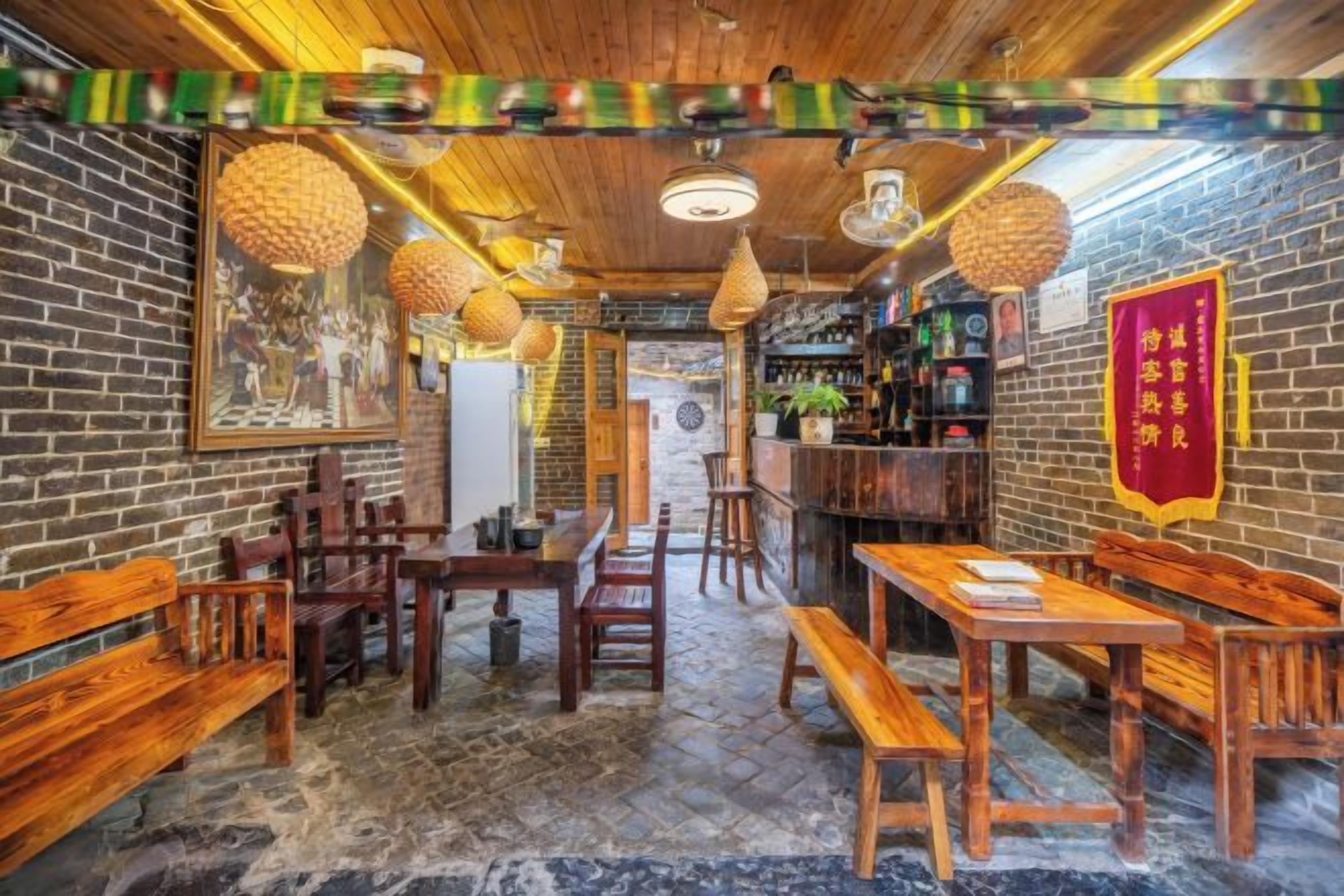 Un interior de restaurante con paredes de ladrillo, muebles de madera, faroles colgantes y un estandarte rojo.