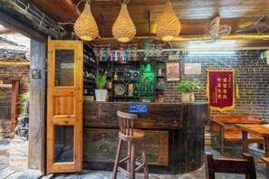 A bar area with a wooden counter, stools, and hanging light fixtures. - By Chance Bar&Inn (Zhaoping)