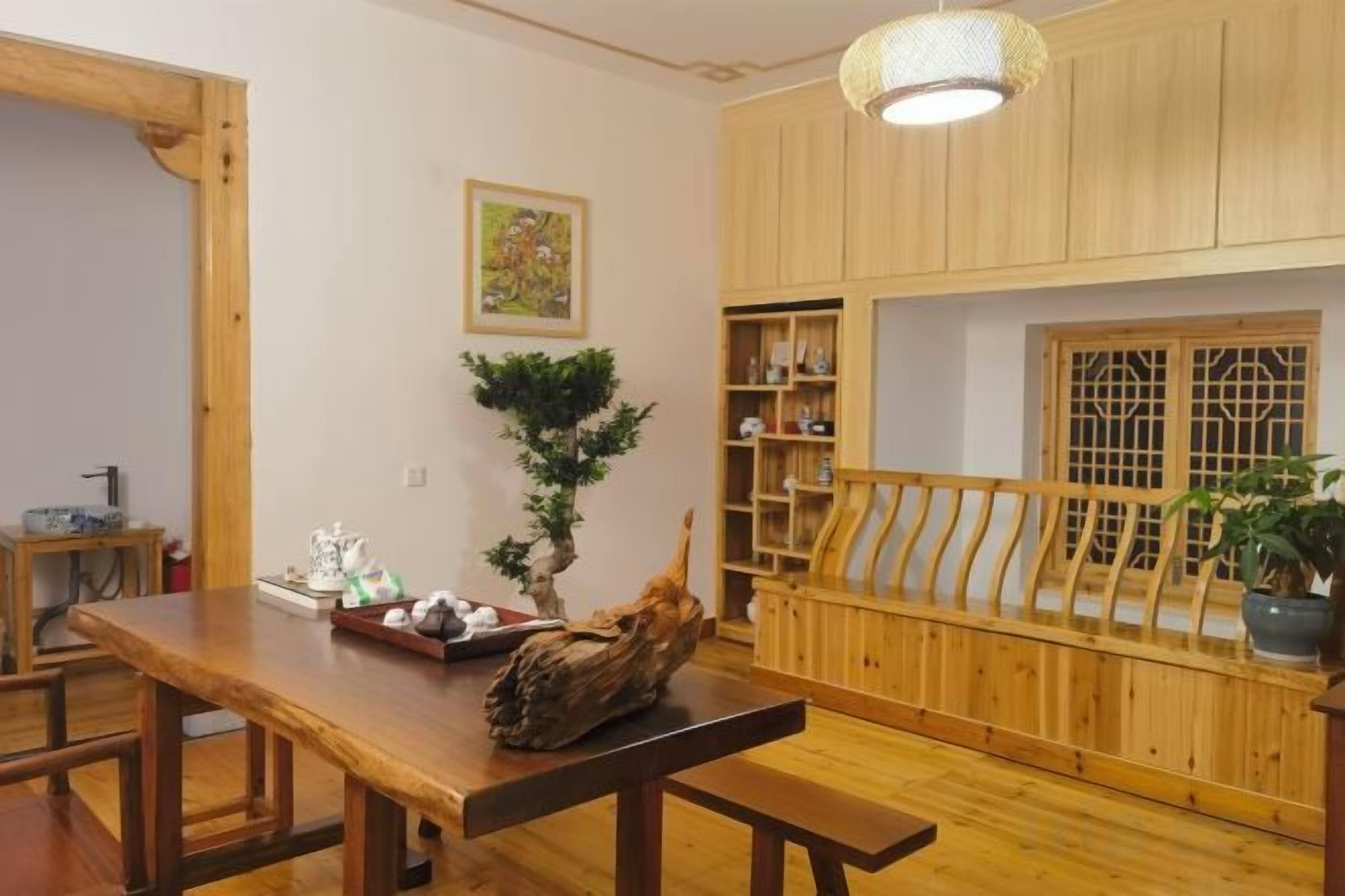Una habitación tradicional japonesa con una mesa de comedor de madera, bancos, una lámpara colgante y una estantería de madera.
