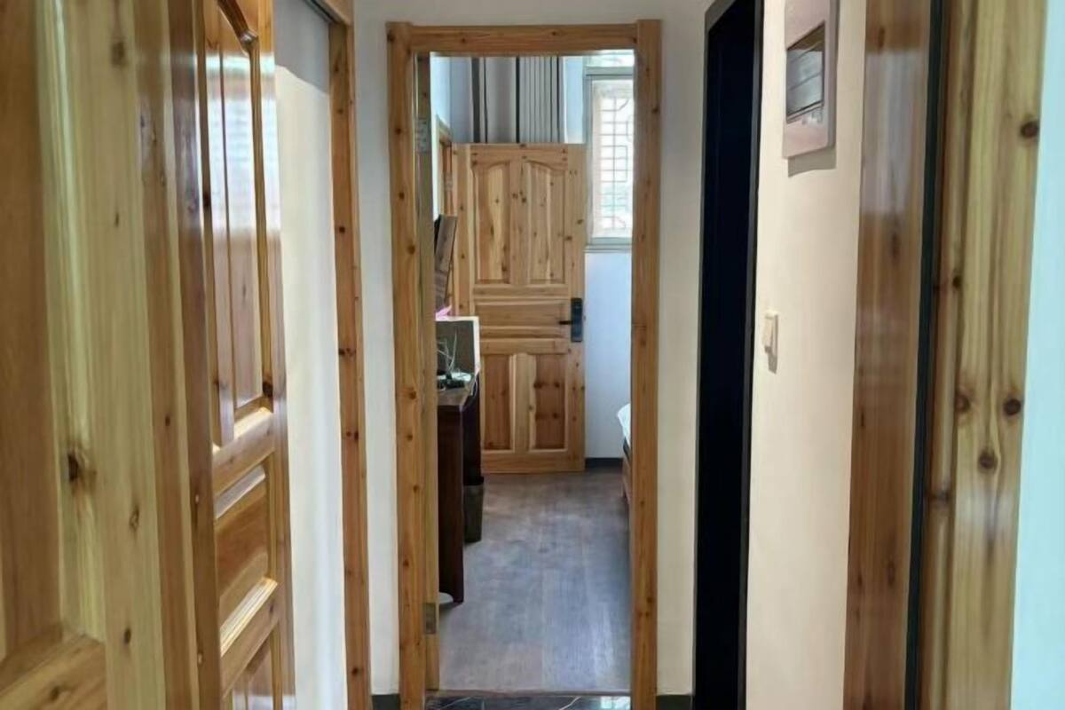 Un pasillo de madera que conduce a una habitación con cama y ventana.