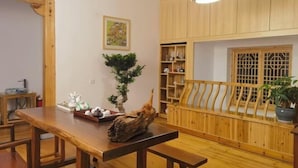 A wooden dining table with benches, a potted plant, and a shelf with various items. - Guankeng Hotel (Wuyuan)