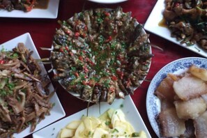 A variety of dishes on a table, including a large platter of stuffed grape leaves and other assorted foods. - Guankeng Hotel (Wuyuan)