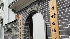 A building with a black brick facade and wooden signage with Chinese characters. - Guankeng Hotel (Wuyuan)