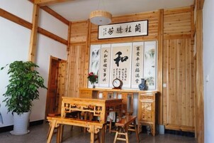 Una habitación japonesa tradicional con paredes de madera, suelo de estequilla, una mesa baja con cojín y un pergamino colgante con caligrafía.