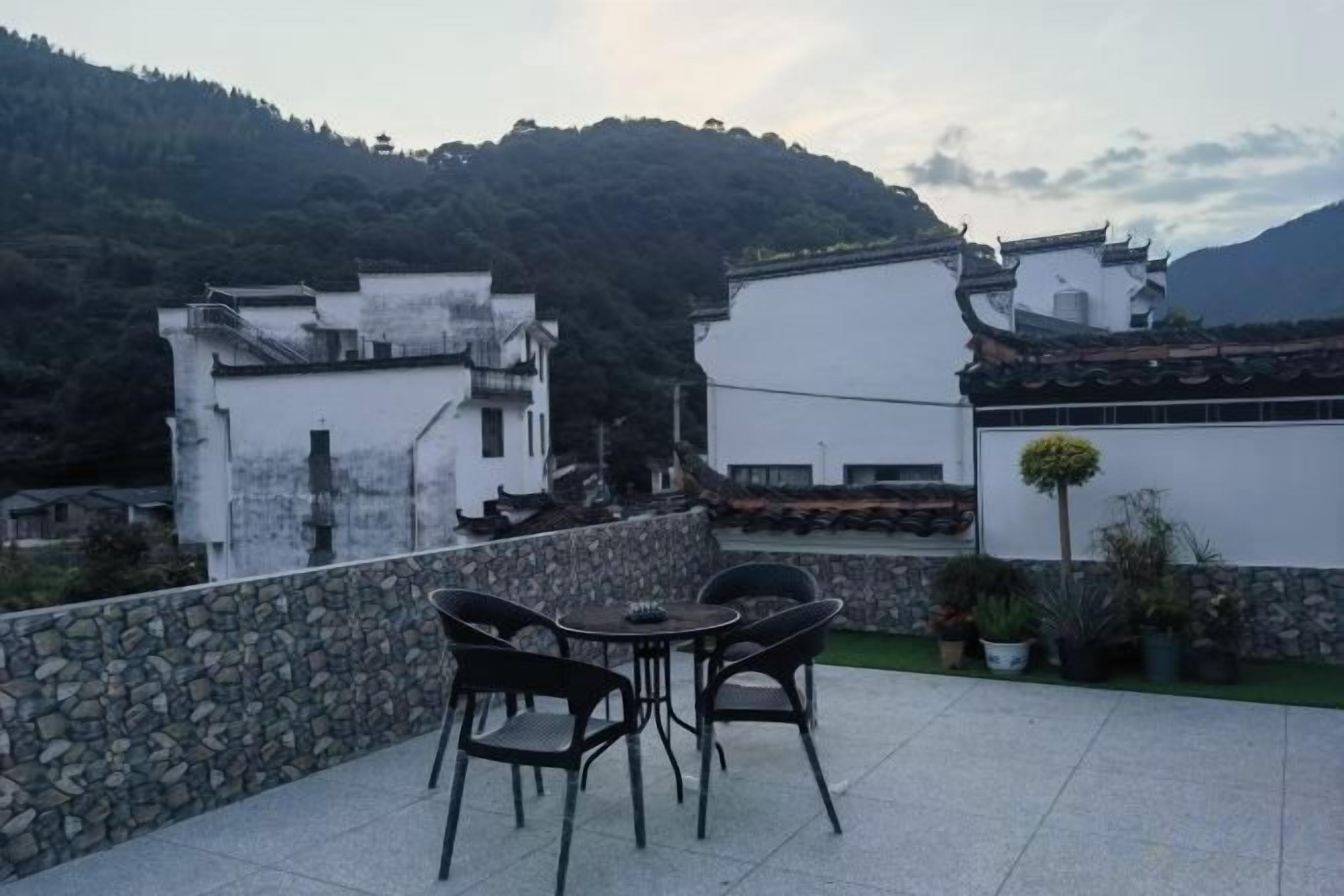 A terrace with a table and chairs, overlooking a mountainous area with traditional buildings.