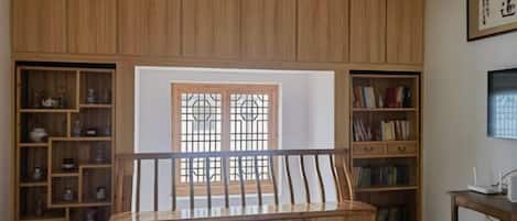 A room with a wooden bench, bookshelves, and a window with a grid pattern.