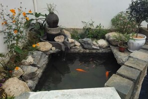 A koi pond with a stone bridge, surrounded by rocks and plants. - Guankeng Hotel (Wuyuan)