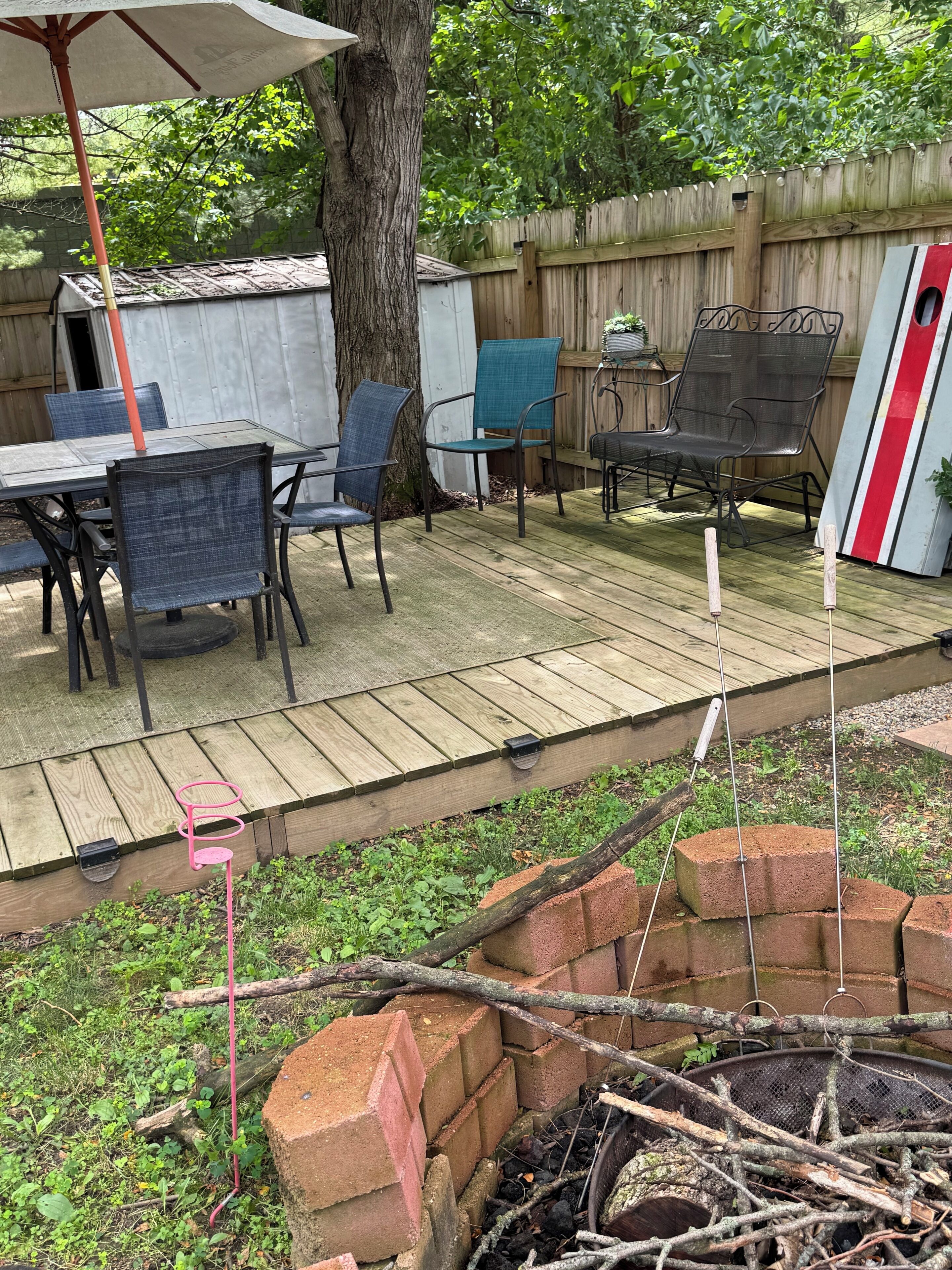 A wooden deck with outdoor furniture, a brick fire pit, and a wooden fence.