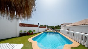 Ein Swimmingpool mit weißem Zaun und einem Gebäude im Hintergrund.