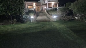 Ein zweistöckiges Haus mit Hauseingang, Treppe und einem gepflegten Rasen.