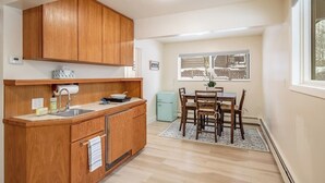 A compact kitchen with wooden cabinets, a sink, and a dining area with a table and chairs.