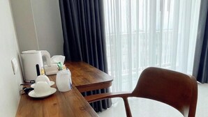 Quarto de hotel com uma mesa de madeira, uma cadeira, uma chaleira e uma cafeteira.
