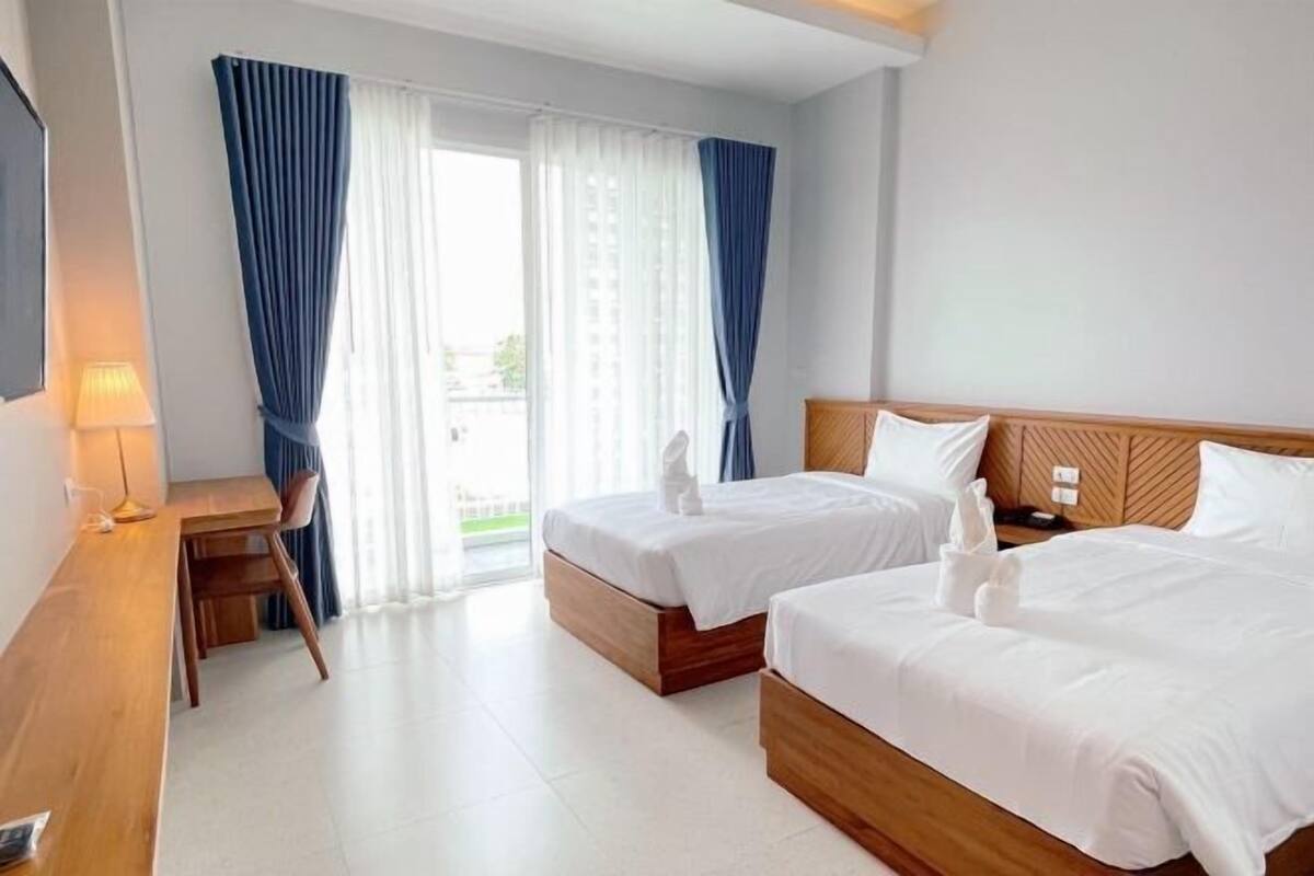 Habitación de hotel con dos camas, un escritorio y vistas al exterior.