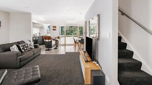 A modern living room with a sofa, a TV, and a staircase.