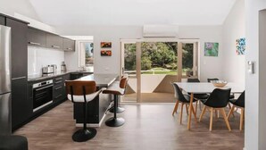 A modern kitchen with a dining area, featuring a large window and a view of the outdoors.