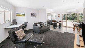 A modern living room with a sofa, a coffee table, and a dining area with chairs.