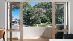 A room with a sliding glass door leading to a balcony with a view of trees and a road.