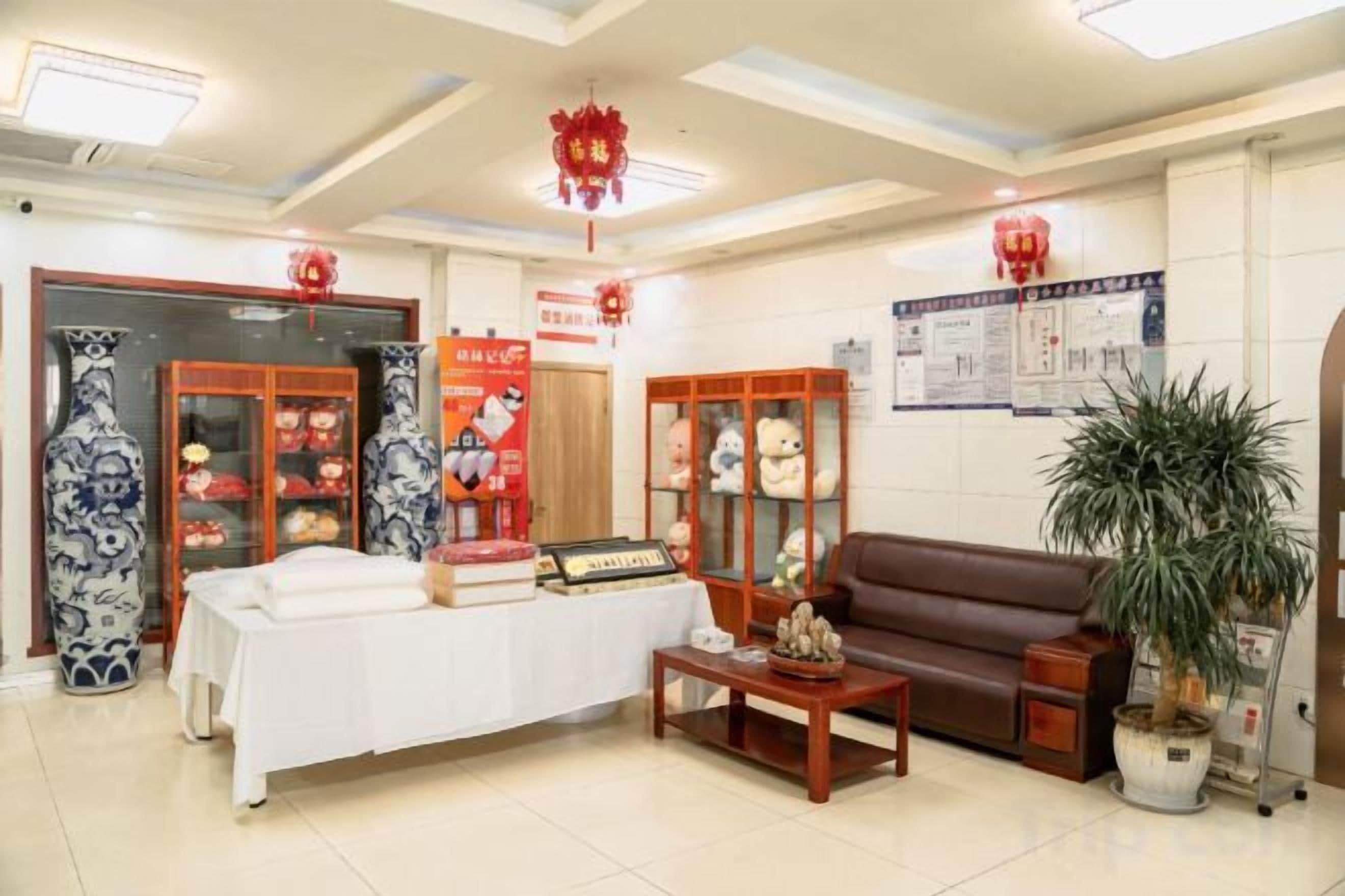 Ein Empfangsbereich mit einer Rezeption, einem braunen Sofa, einer Zimmerpflanze und traditioneller chinesischer Dekoration.