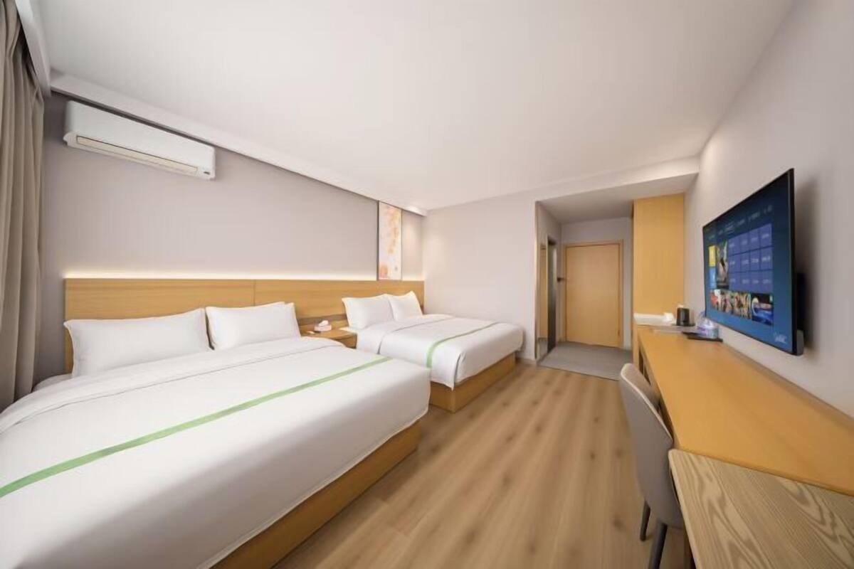 Hotellihuone, jossa on kaksi sänkyä, työpöytä, televisio ja ilmastointilaite.