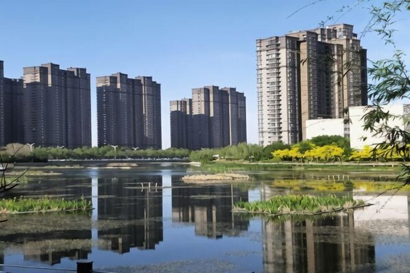 A river with reflections of buildings, surrounded by greenery and a clear sky. - GreenTree Zhixuan Hotel (Dezhou Bus Train Station Black Horse Antiques Debai Plaza) (Dezhou)