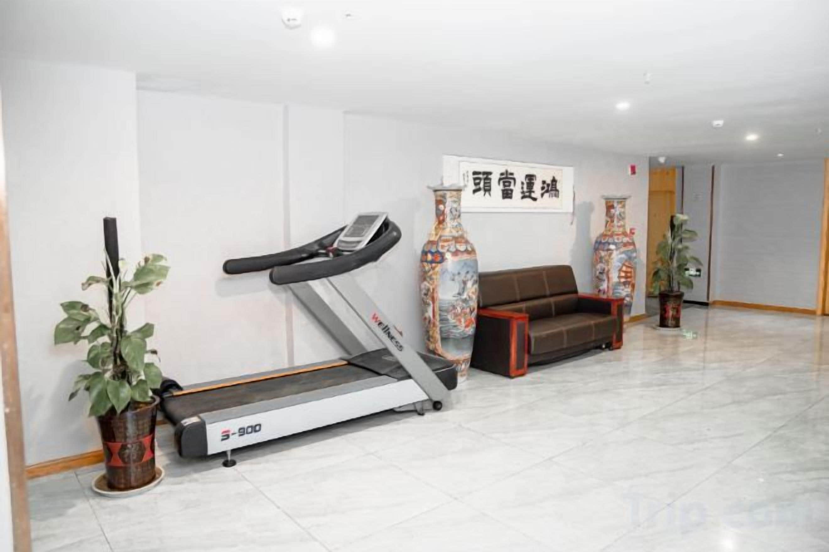 A fitness area with a treadmill, a sofa, and decorative vases.