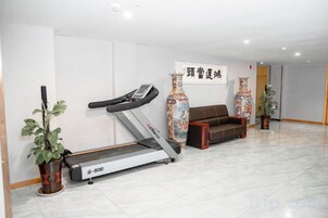 A fitness area with a treadmill, a sofa, and decorative vases.