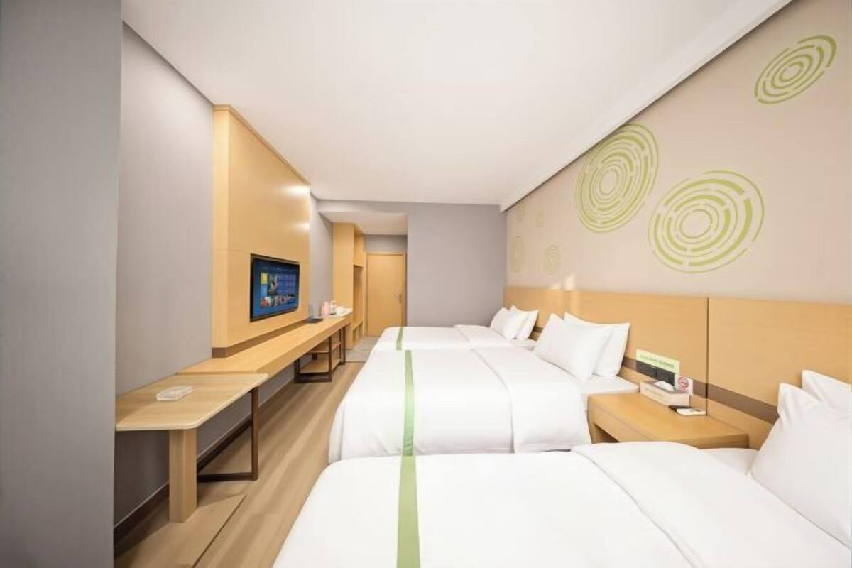 Hotellihuone, jossa on kaksi sänkyä, työpöytä, televisio ja seinä, jossa on pyöreitä kuvioita.