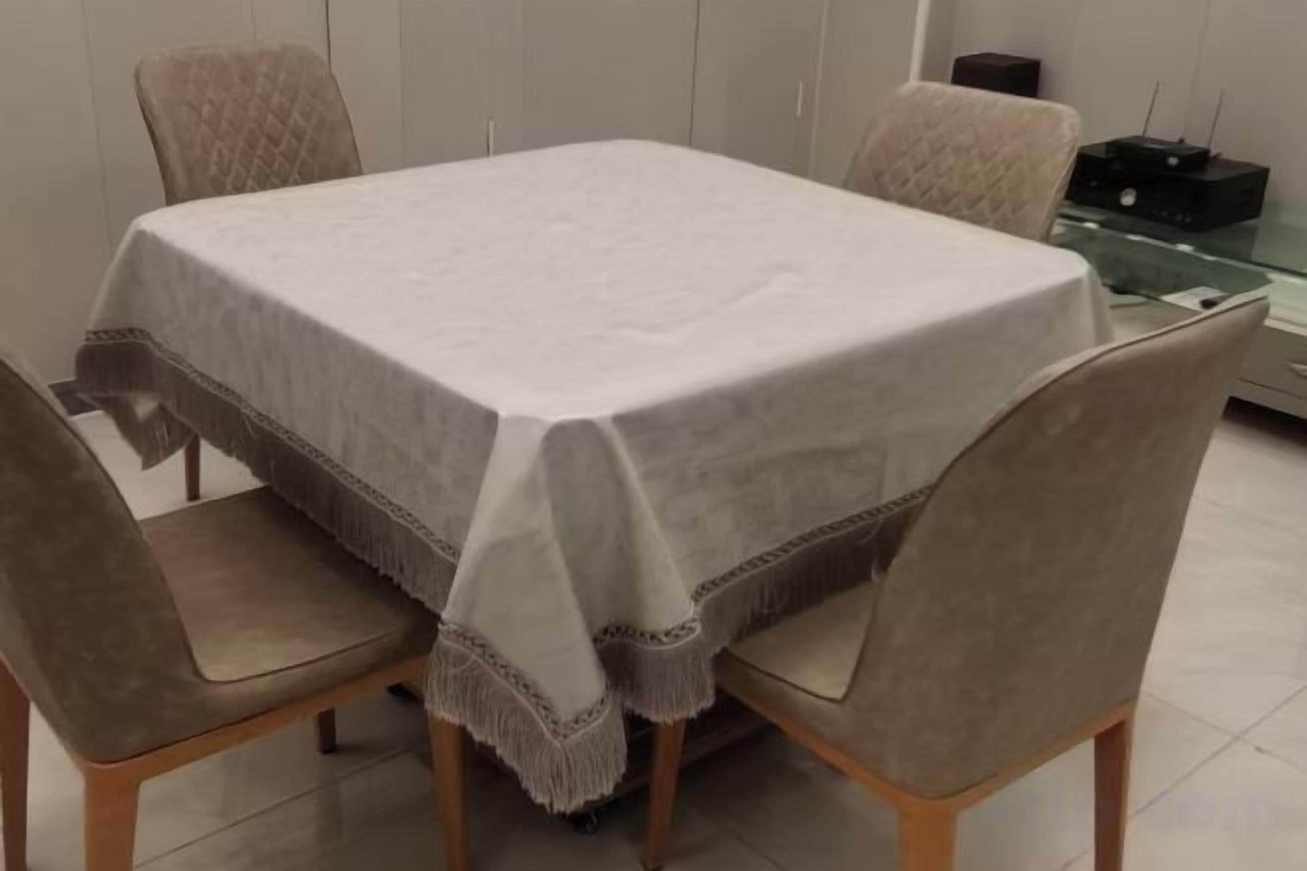 A dining table with a white tablecloth, surrounded by four chairs.
