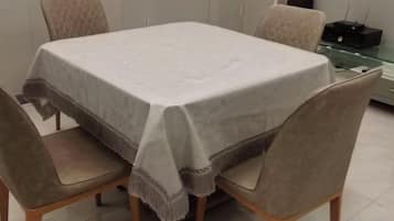 A dining table with a white tablecloth, surrounded by four chairs.