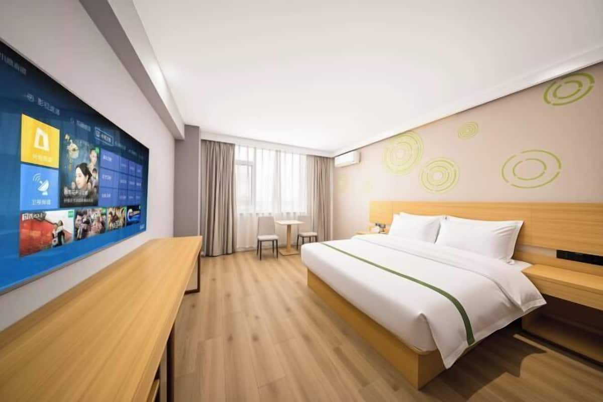 Hotellihuone, jossa on sänky, työpöytä, tuoli ja televisio, josta voi katsoa useita eri kanavia.