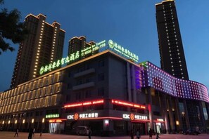 Un edificio a più piani con insegne illuminate, un ristorante KFC e un ampio parcheggio.