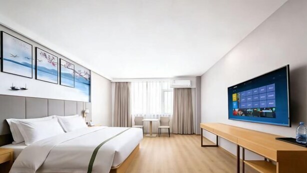 A hotel room with a bed, a desk, a TV, and a window with curtains. - GreenTree Zhixuan Hotel (Dezhou Bus Train Station Black Horse Antiques Debai Plaza) (Dezhou)