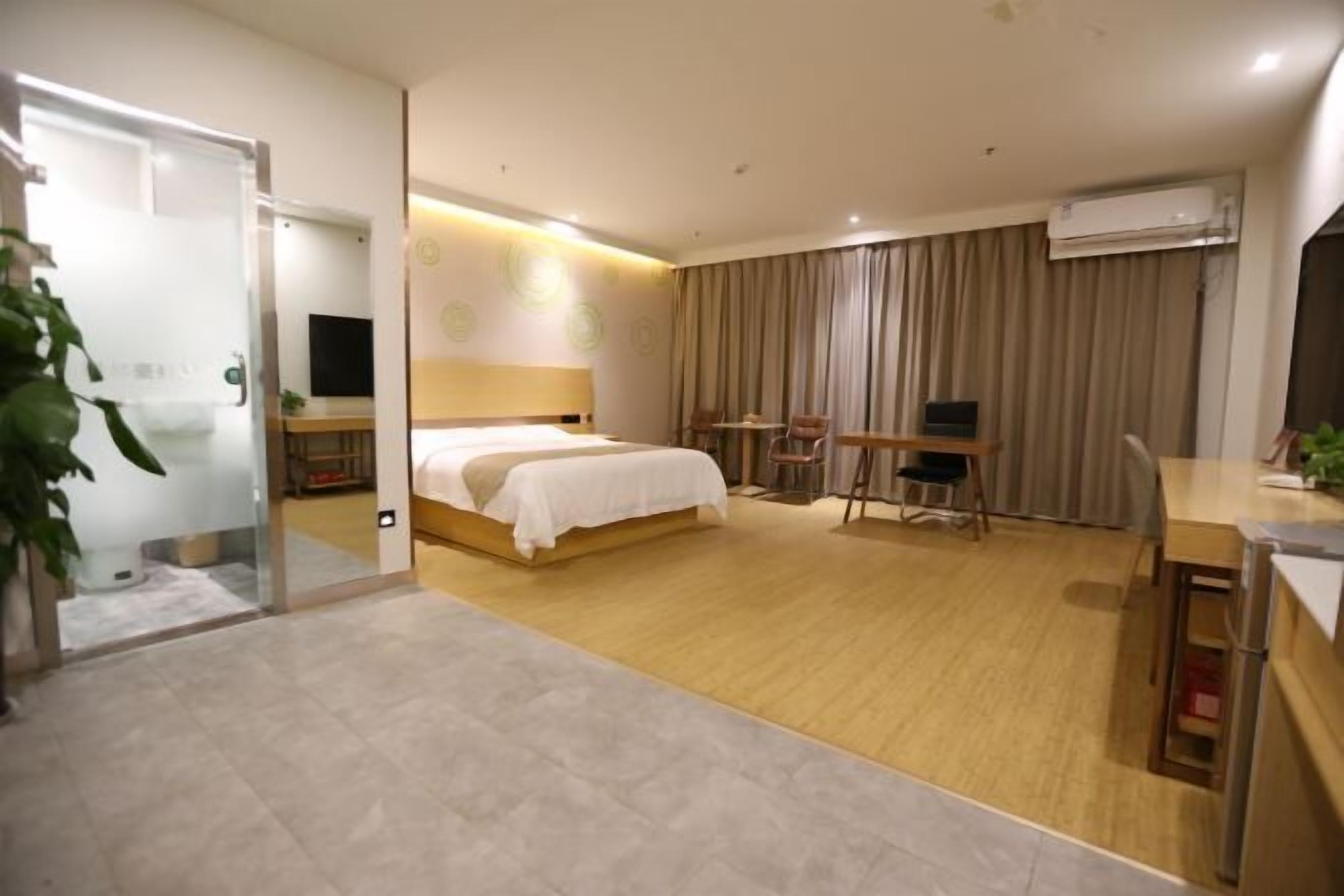 Ett modernt hotellrum med en säng, ett skrivbord, en stol och en luftkonditioneringsanläggning.