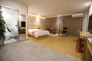 A modern hotel room with a bed, a desk, a chair, and an air conditioning unit.