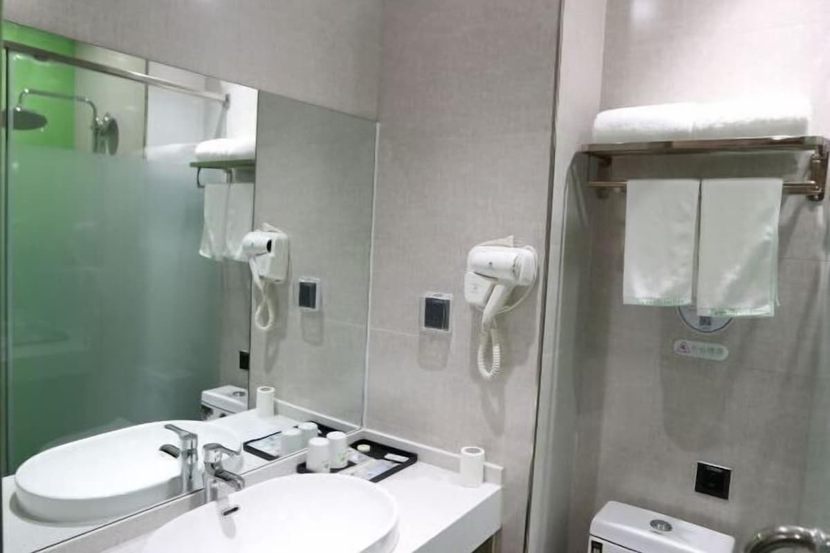 A modern bathroom with two sinks, a large mirror, and a glass-enclosed shower.