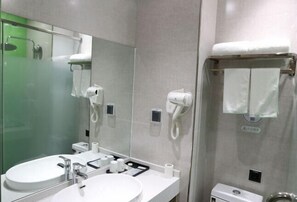 A modern bathroom with two sinks, a large mirror, and a glass-enclosed shower.