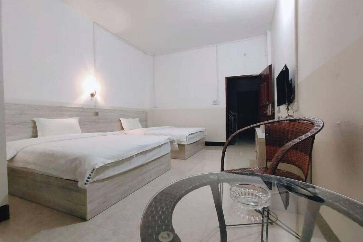 Une chambre d’hôtel avec un lit, une petite table, une chaise, un téléviseur fixé au mur et une porte donnant sur une autre pièce.