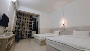 Een hotelkamer met twee enkele bedden, een bureau met stoel, een flatscreen televisie en een gordijn met een patroon.