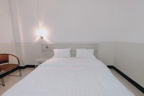 A hotel room with a bed, a nightstand, and a chair. - Youke Hotel (Baise)