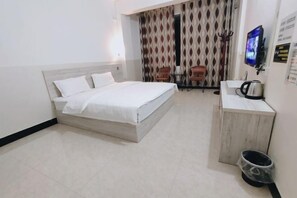 A hotel room with a bed, a small table with chairs, a TV, and a kitchenette area. - Youke Hotel (Baise)