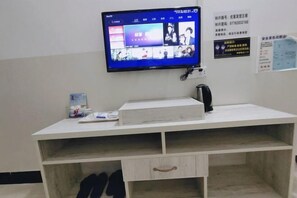 A room with a flat-screen TV mounted on the wall, a white desk with drawers, and a poster on the wall. - Youke Hotel (Baise)